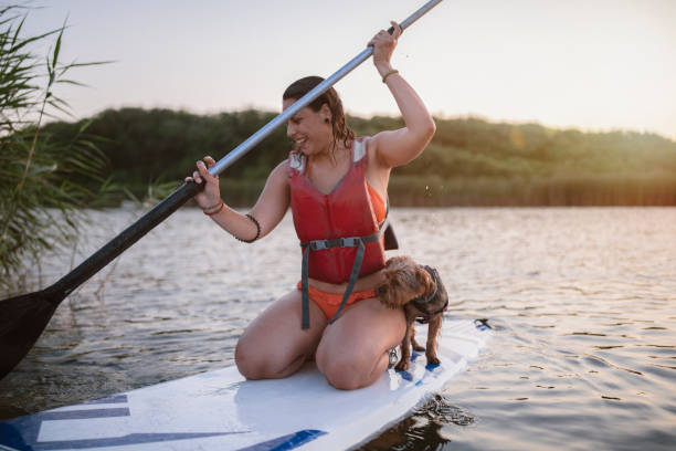 istock Young Attractive Woman is Paddleboarding At The River With Her Dog 1265734954