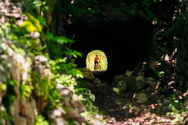 Photo of cyclist with mountain bike at the end of a tunnel