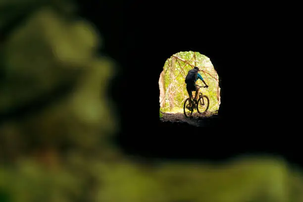 Photo of biker in mountain bike at the end of a tunnel