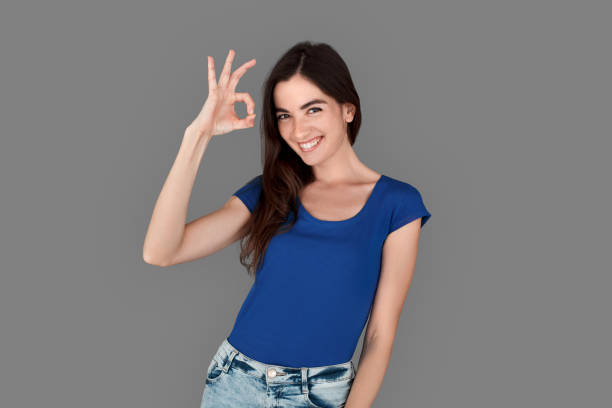 istock Young girl studio standing isolated on grey showing ok sign cheerful 1265736040