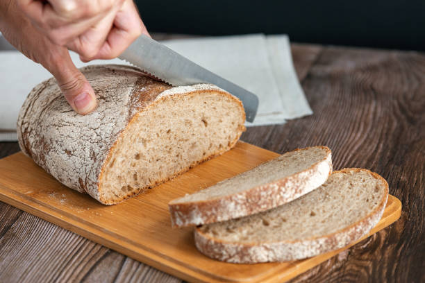 istock Close up of hands cutting a slice of bread 1265736104