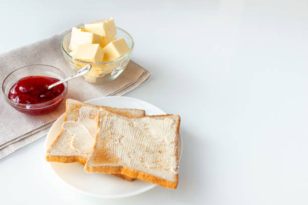 Toast bread, strawberry jam or marmalade and butter on table served for breakfast or brunch. White background. With space for you text