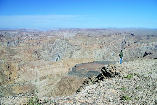 Fish River Canyon, Namibia - Jul 19,2005:  An Asian female tourist is standing up to the edge and looking into the bottom of the canyon.