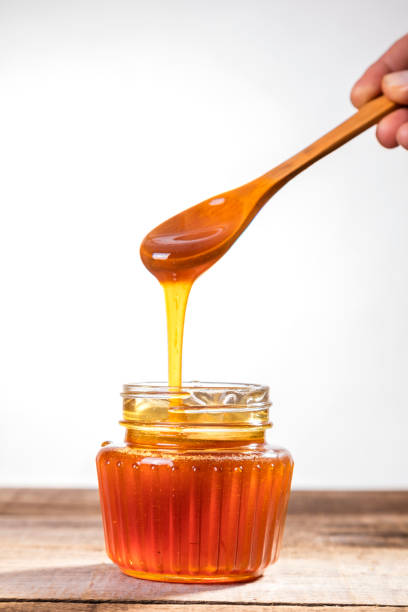 istock Honey dripping from the honey dipper into a glass jar. 1265791044
