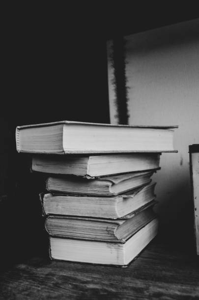 istock Black and white filter on a group of books stacked on a shelf. 1265798347