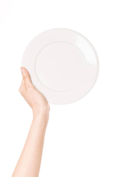 istock woman hand hold a white dish isolated on white. 1265798351
