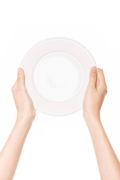 istock woman hand hold a white dish isolated on white. 1265798363