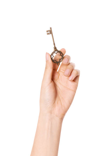 istock woman hand hold a vintage key isolated on white. 1265798364