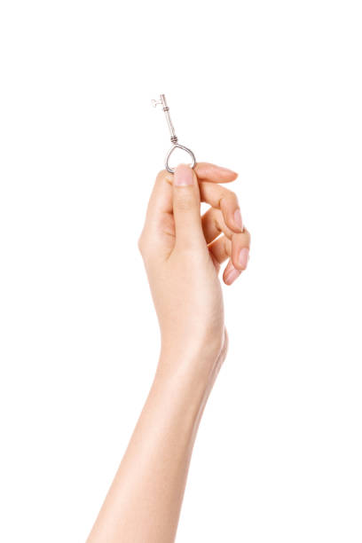 istock woman hand hold a silver vintage key isolated on white. 1265798371