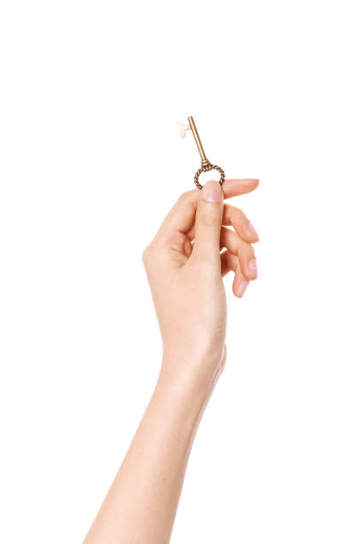 istock woman hand hold a small silver vintage key isolated on white. 1265798372