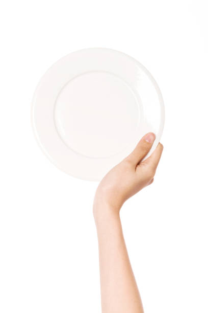 istock woman hand hold a white dish isolated on white. 1265798383
