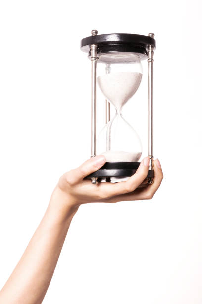 istock woman hand hold a sand timer isolated on white. 1265798420