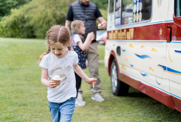 une petite fille heureuse obtenant la crème glacée - camionnette de vendeur de glaces photos et images de collection