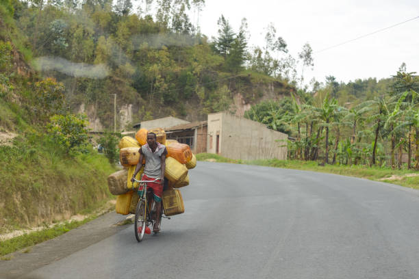man carrying objects in bicycle along rural mountain road Bujumbura / Burundi - October 15, 2016: man carrying objects in bicycle along rural mountain road burundi east africa stock pictures, royalty-free photos & images