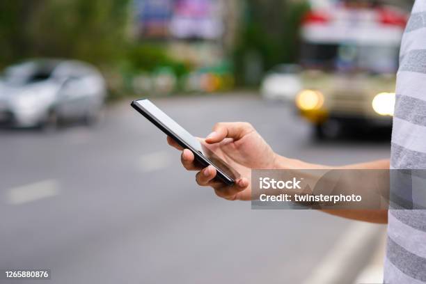 Hand Of Man Using A Mobile Phone On The Street Use Of Transportation App Stock Photo - Download Image Now