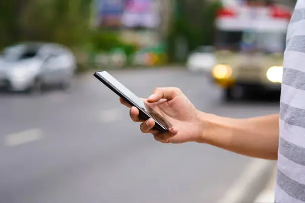 Hand of man using a mobile phone on the street. Use of transportation app