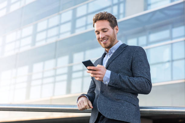 uomo d'affari che usa l'app per telefoni cellulari in ufficio - blazer men suit business foto e immagini stock