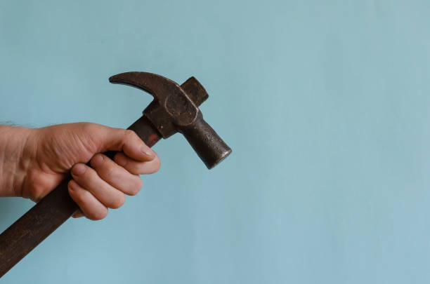 istock Locksmith's hand holds a vintage hammer with a claw hammer. 1265900998