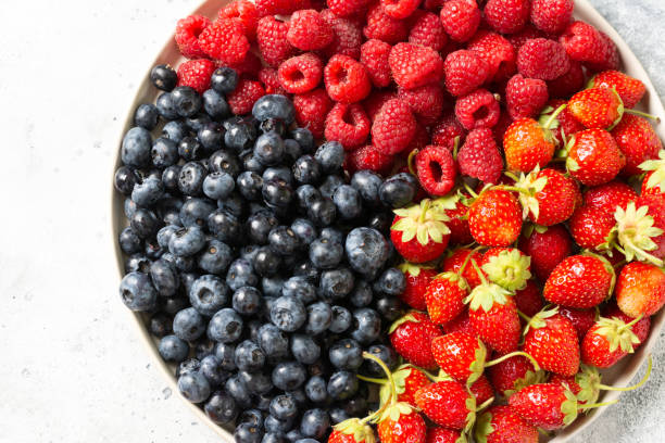 istock Fresh berries. Different berries in a white ceramic plate on a light table. Strawberries, raspberries and blueberries on a plate. Top view with space for text 1265912275