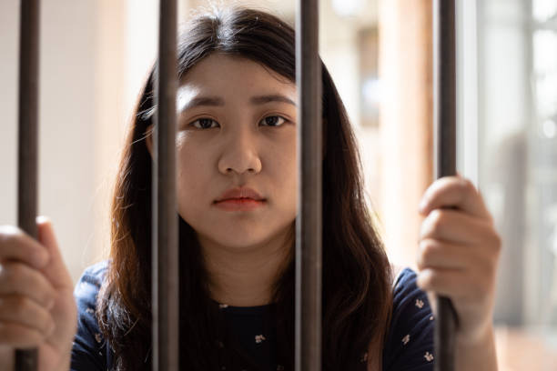 no freedom girl teen in jail hand at cage looking camera no freedom girl teen in jail hand at cage looking camera child arrest stock pictures, royalty-free photos & images