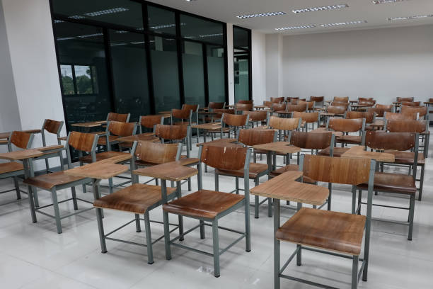 istock Empty school classroom with many wooden chairs. Wooden chairs in classroom. Empty classroom with vintage tone wooden chairs. Empty college classroom. Education stock photo. 1265921296
