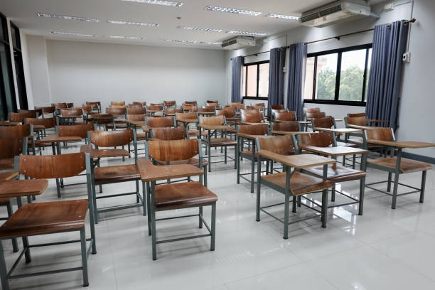 istock Empty school classroom with many wooden chairs. Wooden chairs in classroom. Empty classroom with vintage tone wooden chairs. Empty college classroom. Education stock photo. 1265921302