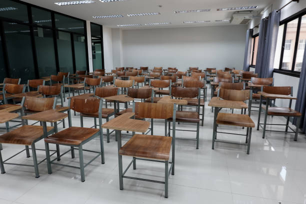 istock Empty school classroom with many wooden chairs. Wooden chairs in classroom. Empty classroom with vintage tone wooden chairs. Empty college classroom. Education stock photo. 1265921303