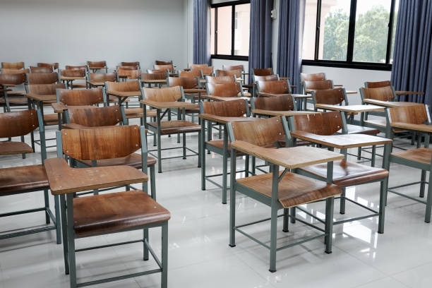 istock Empty school classroom with many wooden chairs. Wooden chairs in classroom. Empty classroom with vintage tone wooden chairs. Empty college classroom. Education stock photo. 1265921313