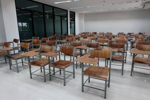 istock Empty school classroom with many wooden chairs. Wooden chairs in classroom. Empty classroom with vintage tone wooden chairs. Empty college classroom. Education stock photo. 1265921316