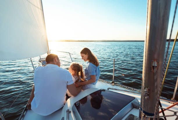 海でヨットデッキセーリングに座っている3人の家族 - sunset yacht luxury sailboat ストックフォトと画像