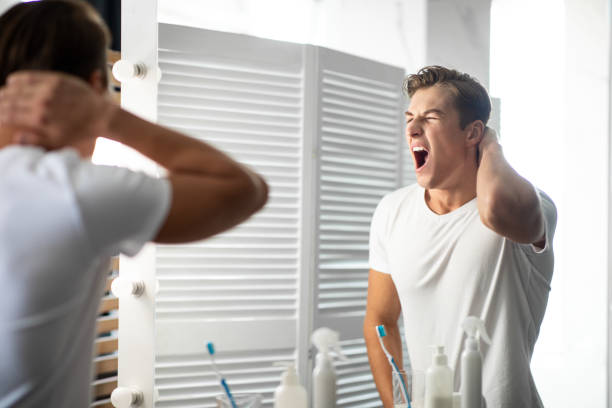 istock Handsome young man looking in the mirror and yawning 1265924472