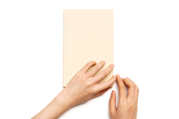 istock woman hand hold a book cover and open isolated on white. 1265930414