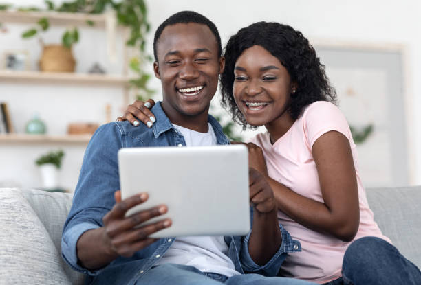 istock Emotional african couple using digital tablet together at home 1265939762