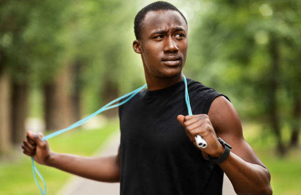 istock Concentrated sporty black guy with jumping rope training at park 1265942854