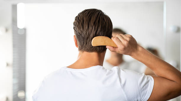 Handsome young man looking in the mirror brushing hair