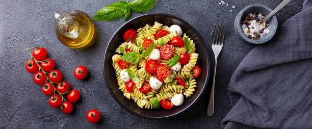 istock Pasta fusilli with mozzarella cheese, tomatoes and basil. Dark background. Top view. 1265944765