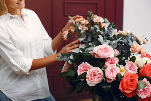 Florisr with flowers. Women makes a bouquete. Cute girl working