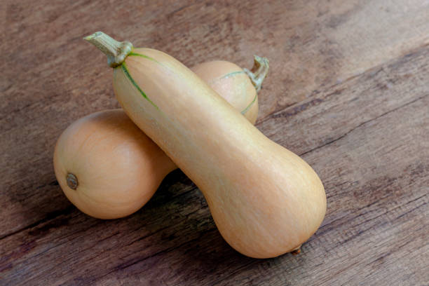 istock Butternut Squash isolated on wooden table. Butternut is a bell-shape fruit with sweet orange-yellow flesh. 1265947592