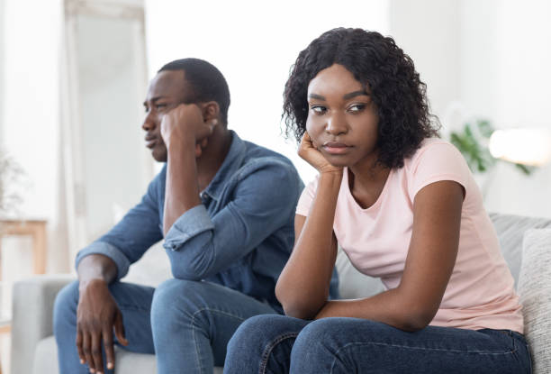 homem e mulher africano frustrados sentados no sofá em casa - human pregnancy pensive women thinking - fotografias e filmes do acervo