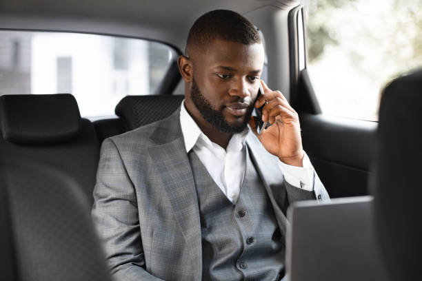 istock Young african businessman using mobile phone and laptop in car 1265956300