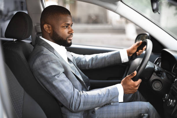 istock Handsome black businessman in suit driving car 1265956534