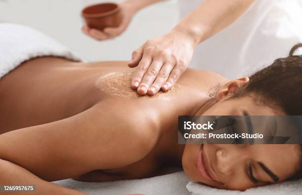 Masseuse Applying Body Scrub On Black Girl Back Stock Photo - Download Image Now - Spa, Exfoliation, The Human Body