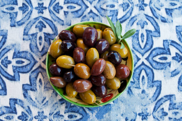Assortment of fresh olives on a plate. Blue background. Close up. Top view. Assortment of fresh olives on a plate. Blue background. Close up. Top view. mediterranean food photos stock pictures, royalty-free photos & images