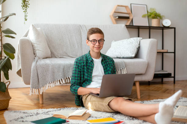 istock Cheerful male teenager doing homework, using laptop 1265957805