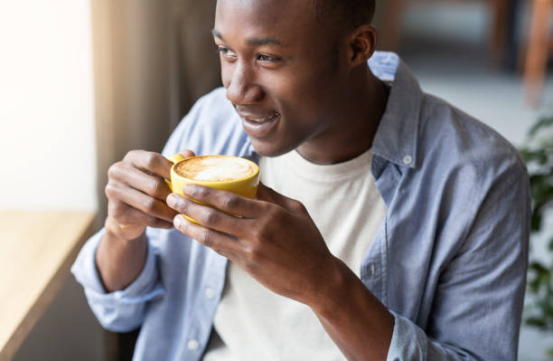 istock Young black man relaxing and drinking aromatic coffee in cafeteria 1265958216