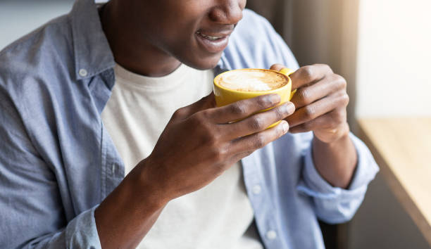 istock Unrecognizable black guy enjoying cup of fresh coffee during break at cafe, closeup 1265964666