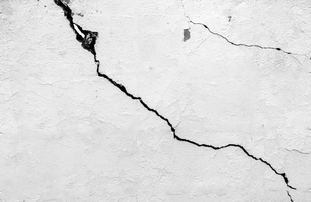 istock The black and white concept of a plain white plastered brick wall with cracks for backgrounds, patterns and textures for backgrounds. Concrete surfaces are slightly rough. Random seamless wall pattern 1265964753