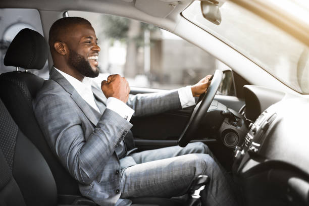 jonge emotionele zwarte zakenman die na succesvolle bedrijfsvergadering drijft - chauffeur beroep stockfoto's en -beelden