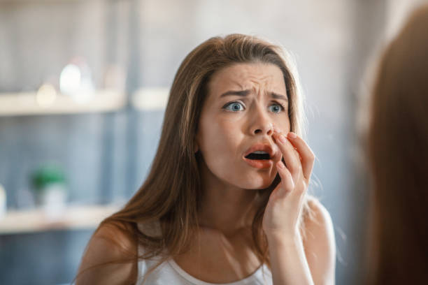 istock Shocked woman touching acne on her cheek while looking in mirror at home 1265965171