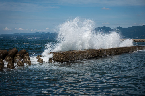 A White sprays of large sea wave are breaking about a breakwater. Close-up. Seascape.